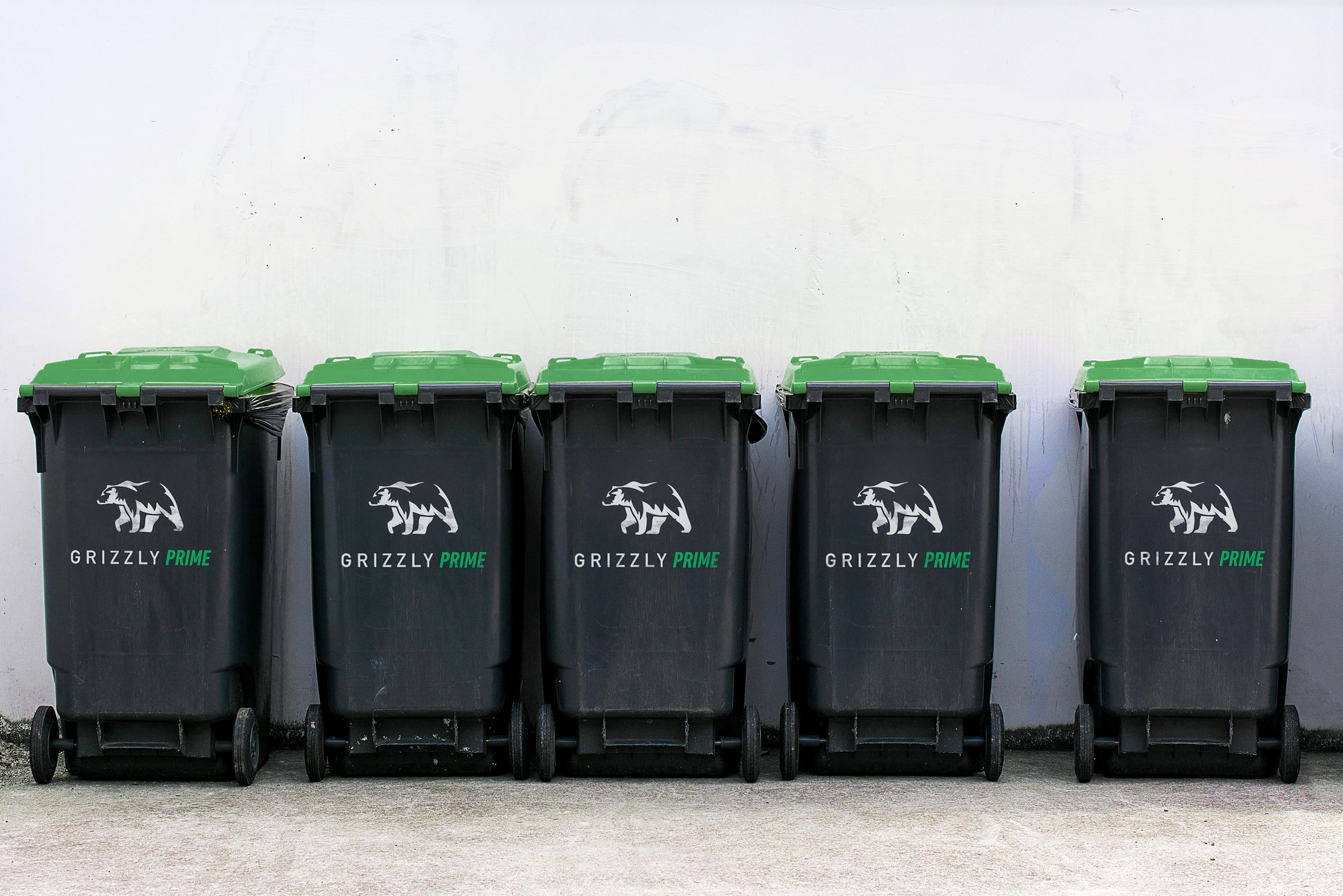 Overfilled trash bags piled beside a wall